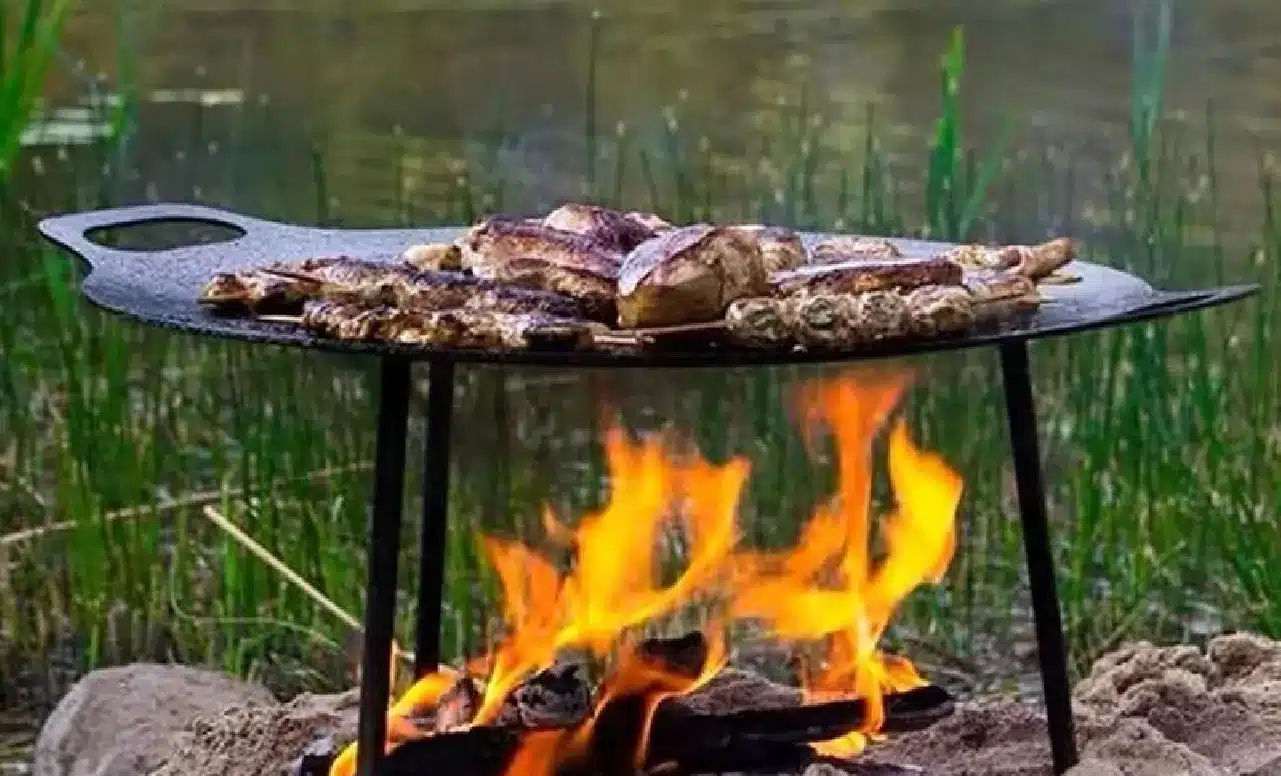 grilovací plát nad otvoreným ohňom pri vode s pripraveným mäsom