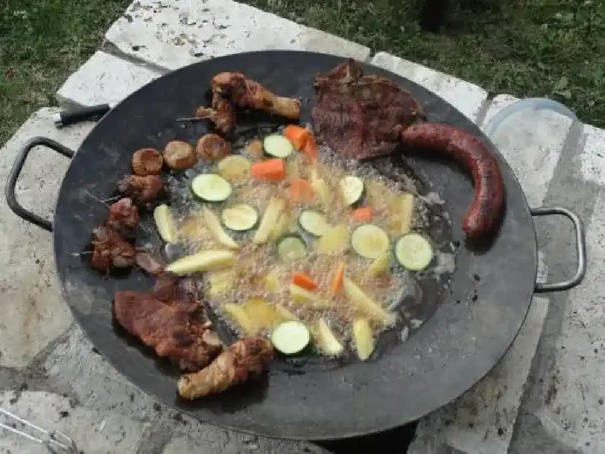 zemiaky, zelenina, klobása a mäso pripravené na veľkom grilovacom pláte